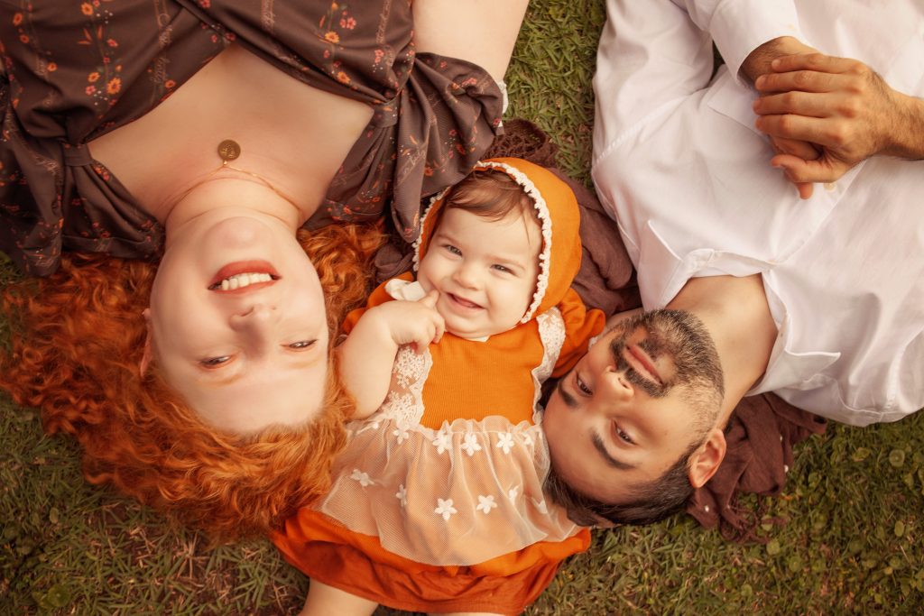 Pais celebrando o primeiro aniversário da filha em um momento íntimo e acolhedor no jardim de casa.